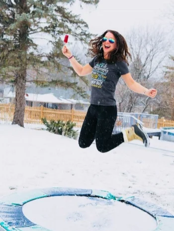 crazy girl with popsicle jumping on a trampoline with snow.