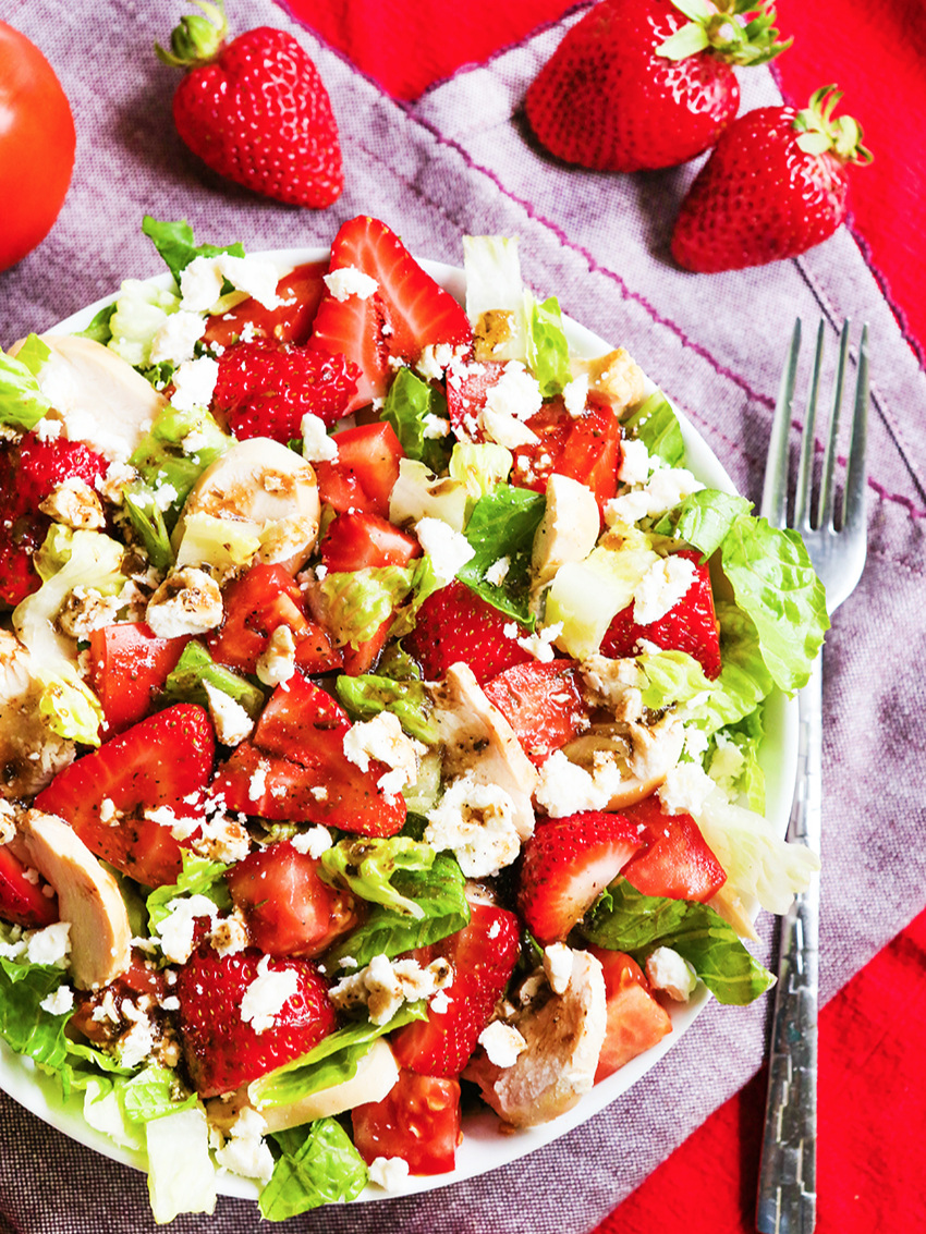 Close up view of Strawberry chicken salad on table cloth with a fork next to it