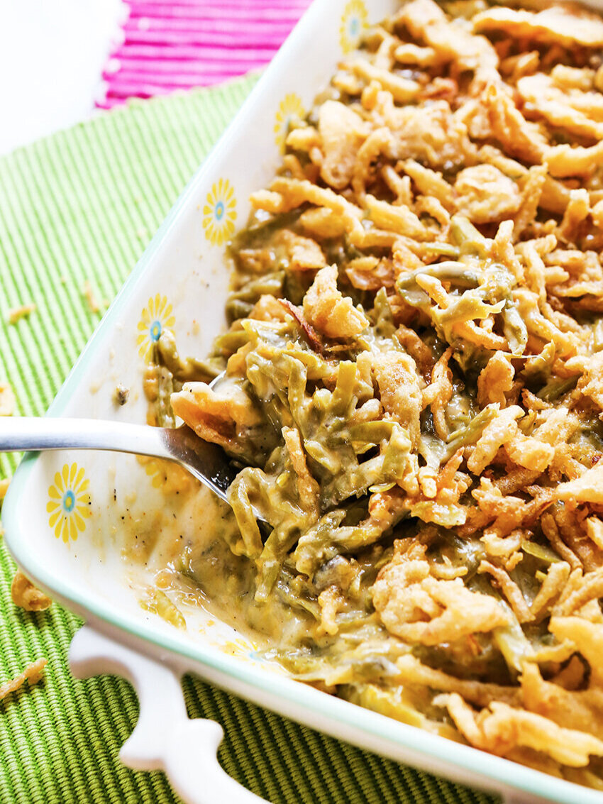 Crispy onions on top of Crockpot Green Bean Casserole with serving spoon