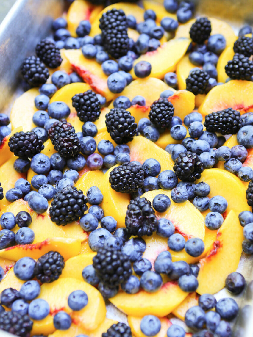 pan of fresh sliced peaches, blueberries and blackberries