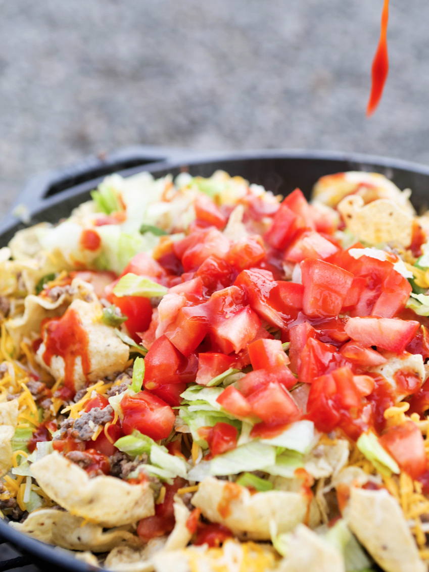 Hot sauce dripping onto campfire nachos 