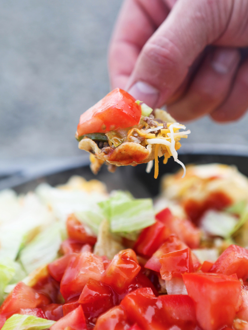 Hand holding chip full of nachos 