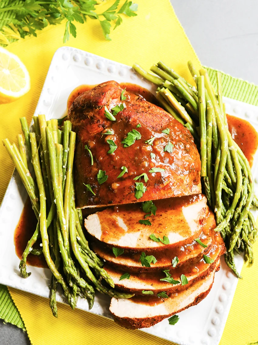 Top view of sliced turkey breast on plate with asparagus 