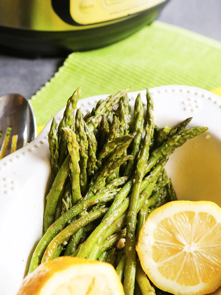 Asparagus in bowl with lemons sitting next to Instant Pot 