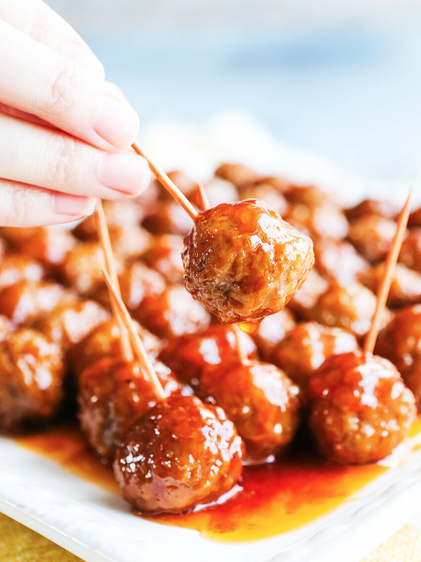  Handing holding toothpick with a meatball stuck into it 