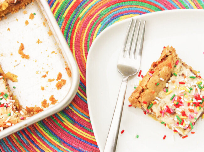 top view piece of cake with sprinkles on plate next to pan 