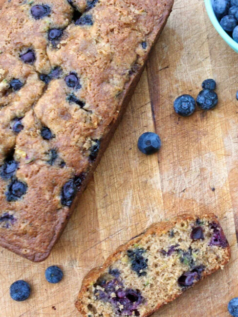  top view of a loaf of blueberry zucchini bread with slices sitting on side 