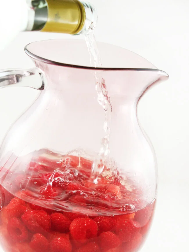  White wine being poured into pitcher of sangria 