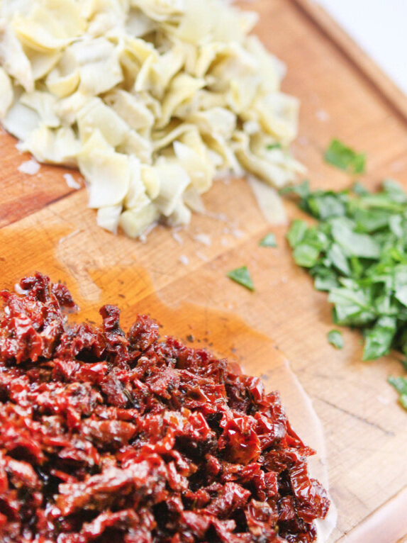  Chopped sun dried tomatoes and artichokes on a cutting board 