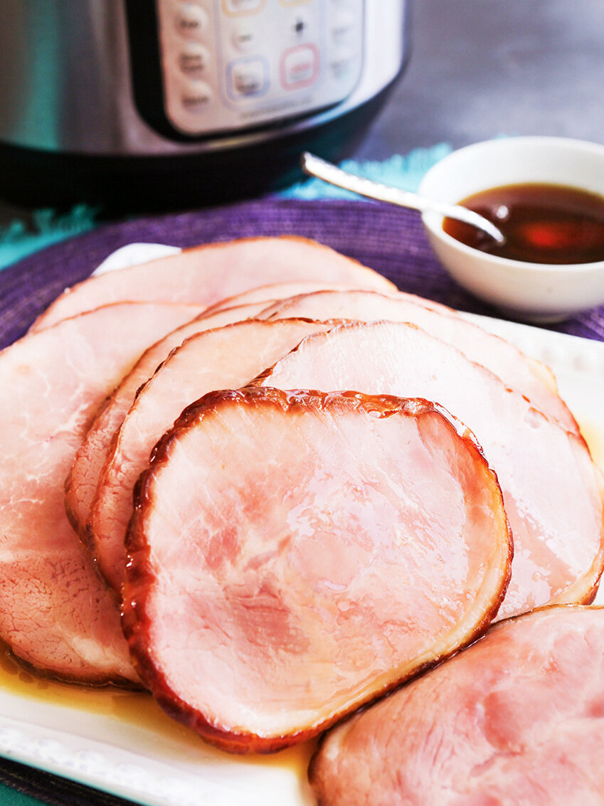sliced ham on serving plate next to instant pot 
