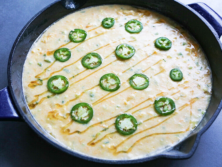  Corn bread in skillet with honey and jalapeno slices ready to be cooked 