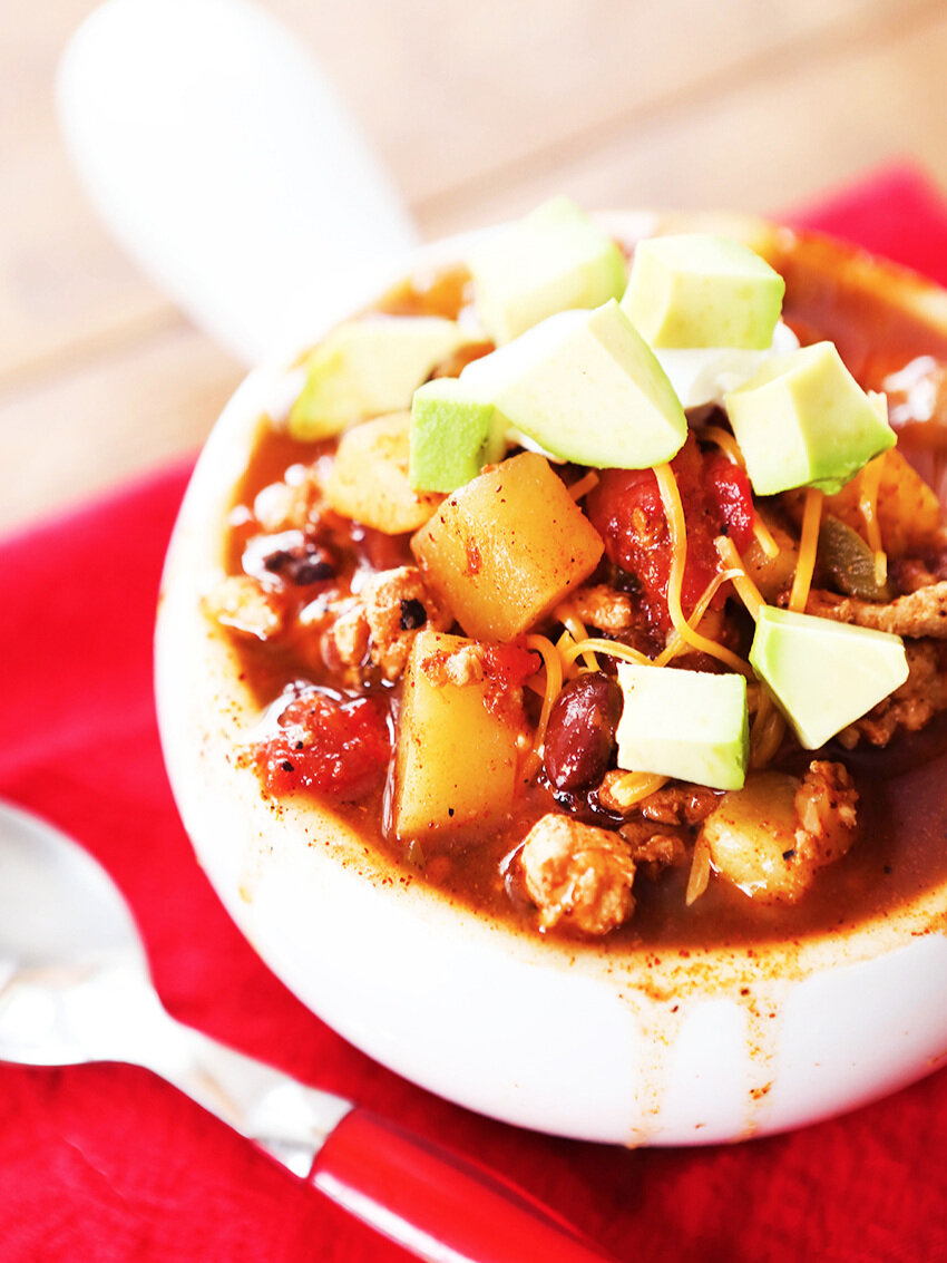  Bowl of turkey chili with avocado pieces on top 