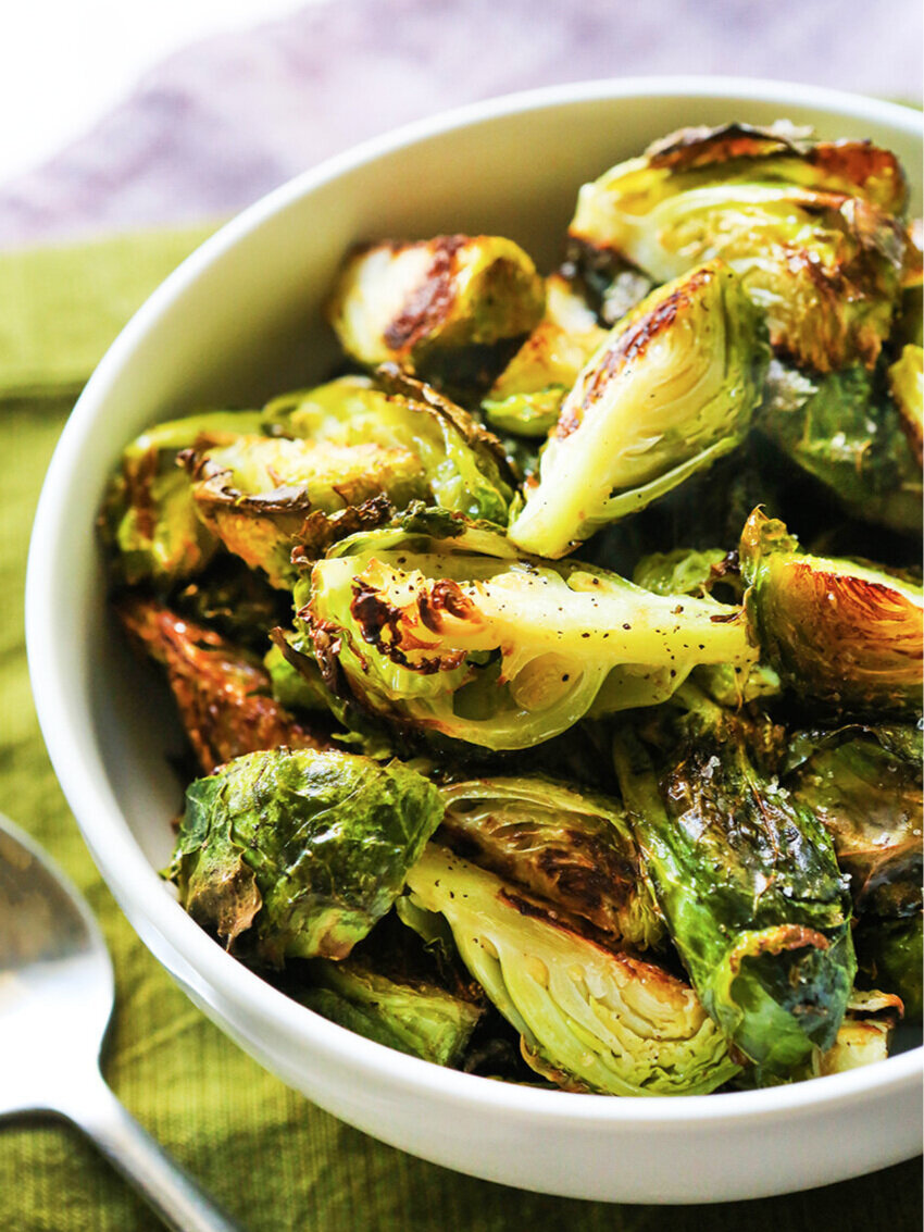 white bowl of roasted brussels sprouts with serving spoon 