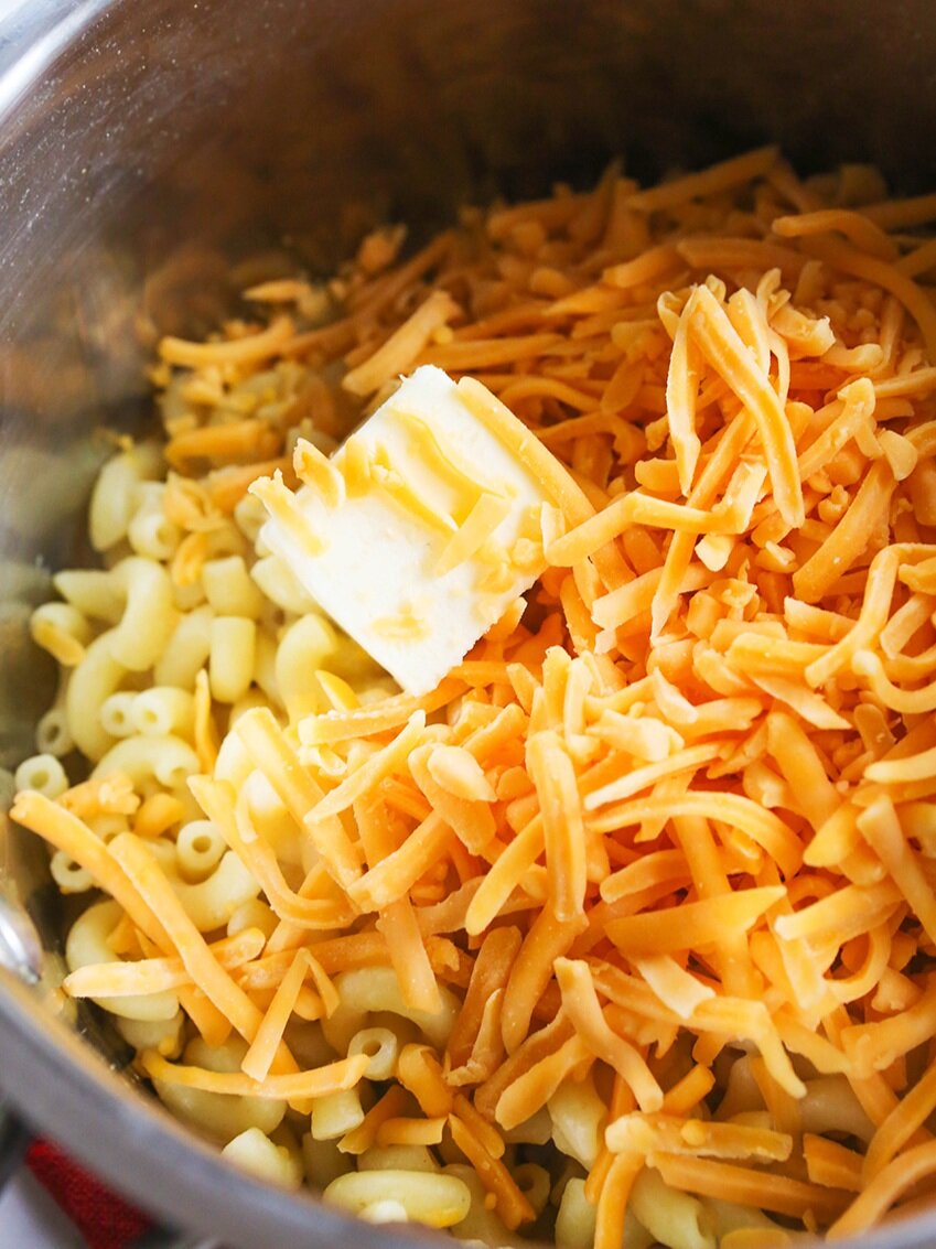 cooked elbow macaroni, shredded cheese and butter in saucepan 