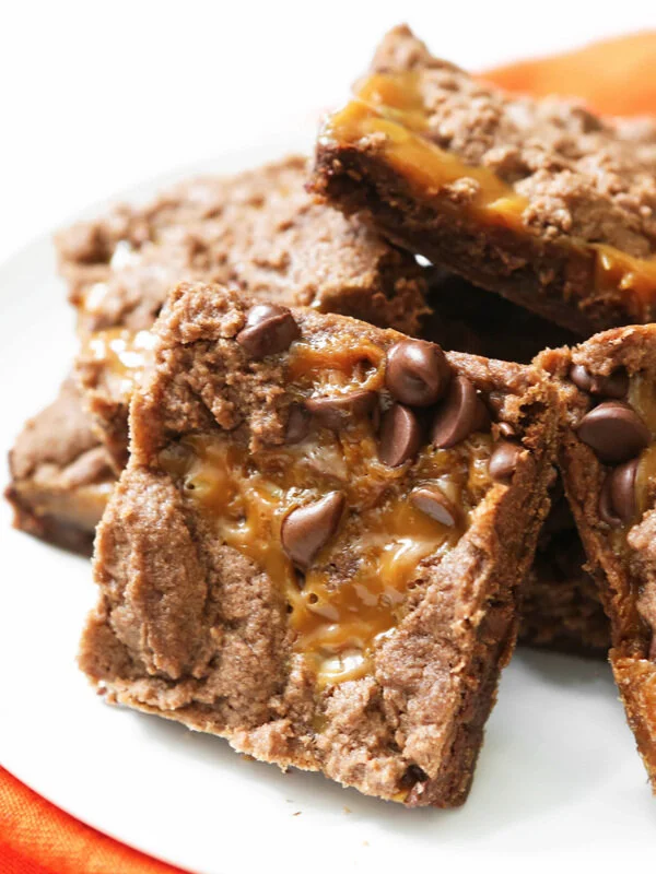 Stack of chocolate caramel brownies on white serving plate 