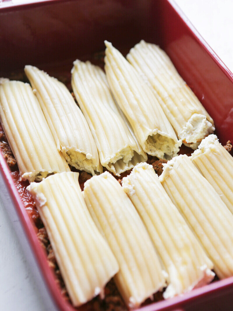 stuffed manicotti noodles lined up in baking dish 