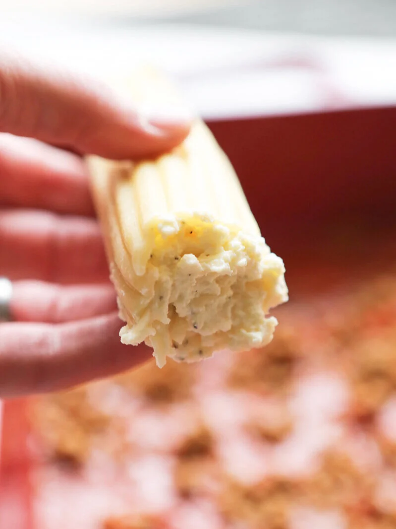 Hand holding a single cheese-stuffed manicotti noodle