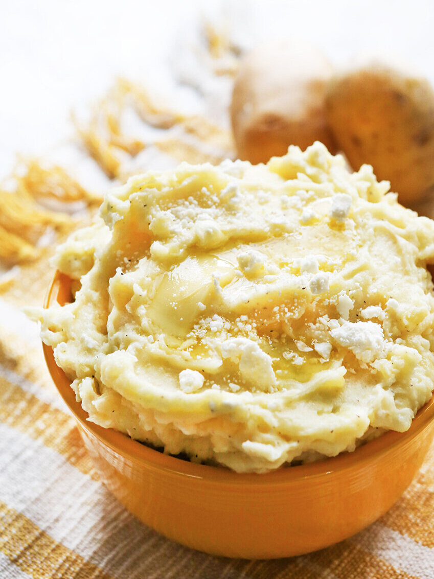 Heaping bowl of mashed potatoes with butter dripping down