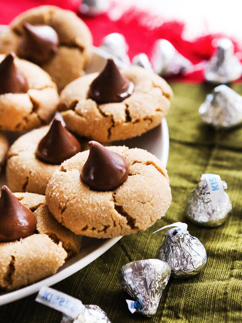 Plate of peanut butter kiss cookies with hershey’s kisses next to it 