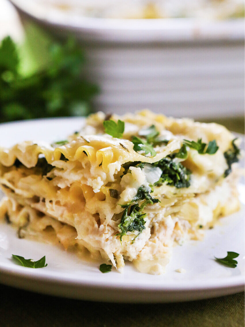 A piece of white lasagna on a plate next to baking dish 