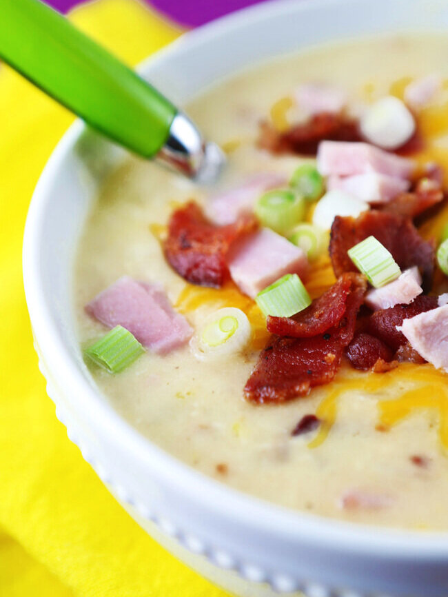  close up of bowl of loaded potato soup with tons of toppings 