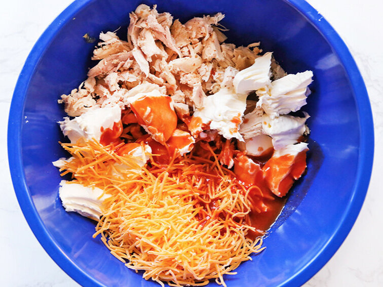 Buffalo chicken dip ingredients in mixing bowl
