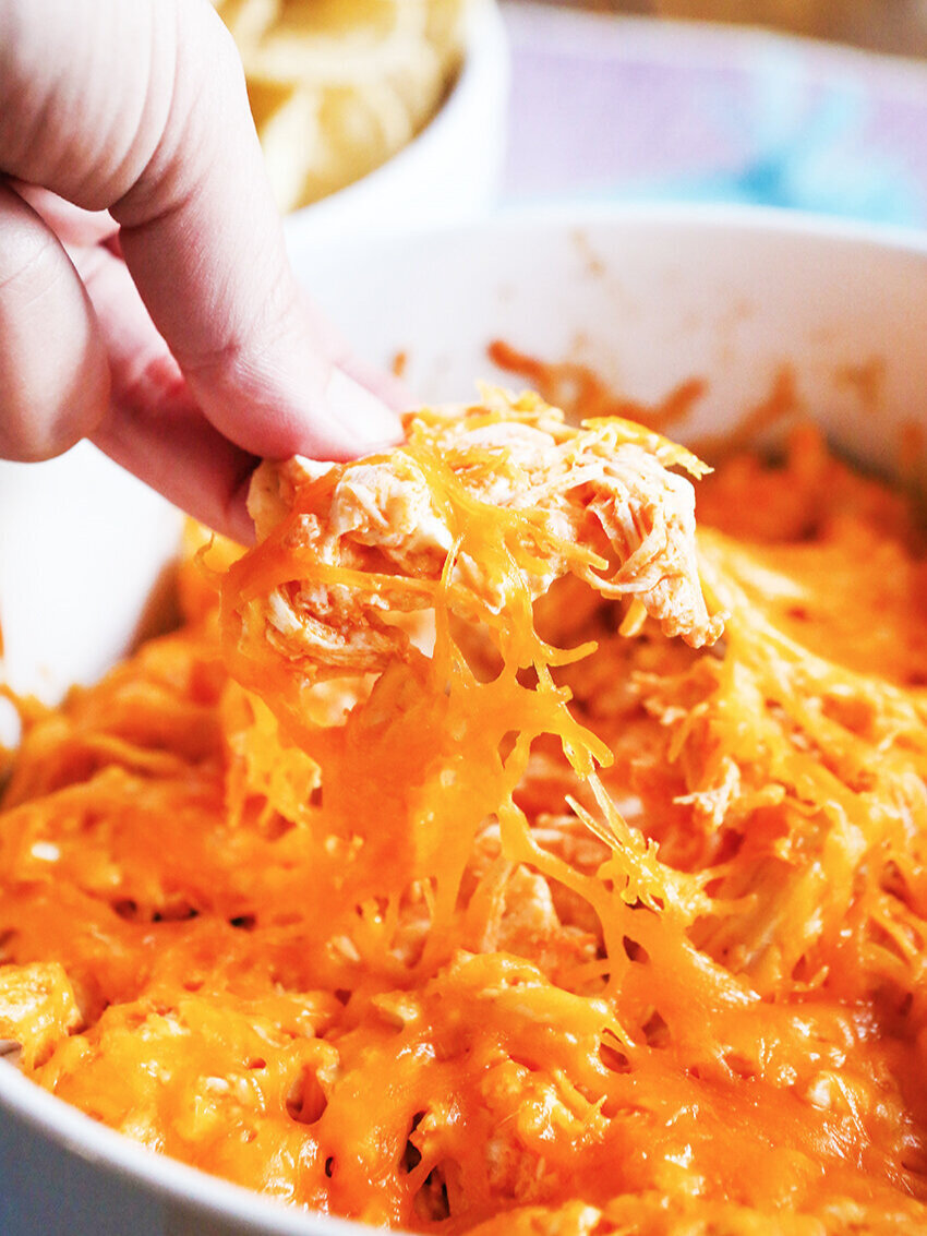 Chip loaded with buffalo chicken dip being pulled from pan