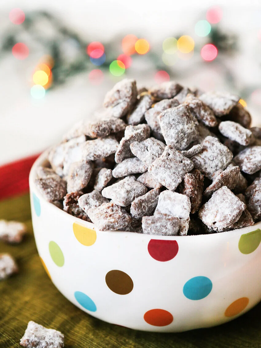 Heaping bowl of puppy chow with christmas lights in background 