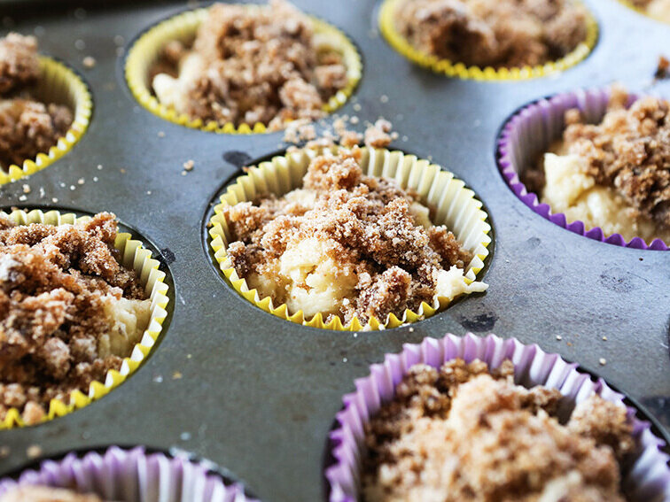Muffin tin filled with liners, batter and topped with crumbs 