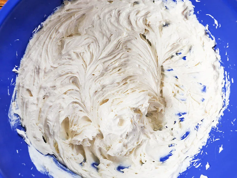 Creamy cheese mixture in blue mixing bowl 