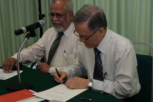 Prof Ho signs the document.