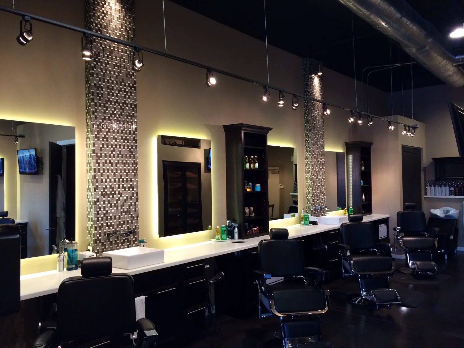 Row of barber stations with backlit mirrors and styling chairs