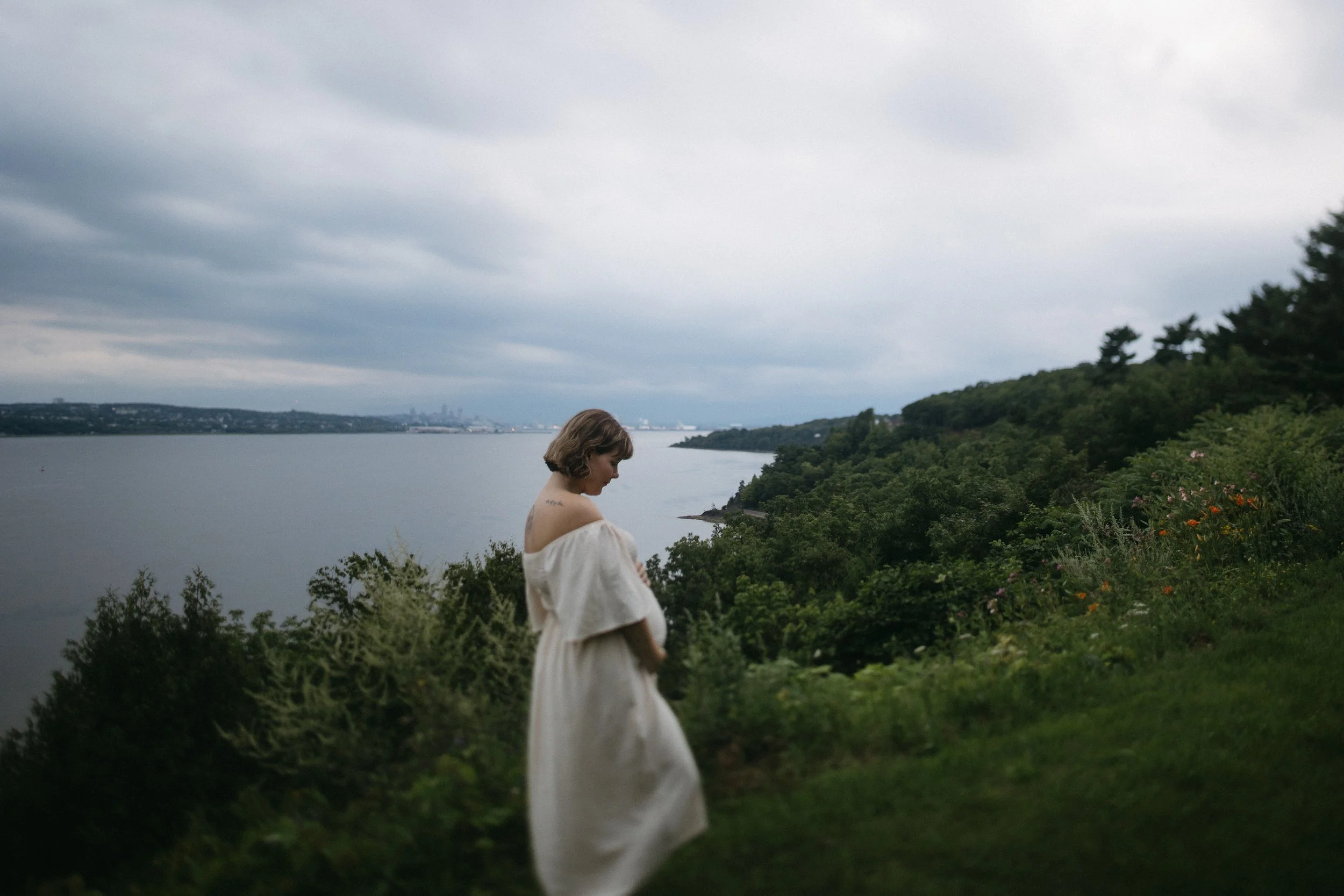 une femme enceinte qui regarde son ventre sur le bord du fleuve dans la ville de québec