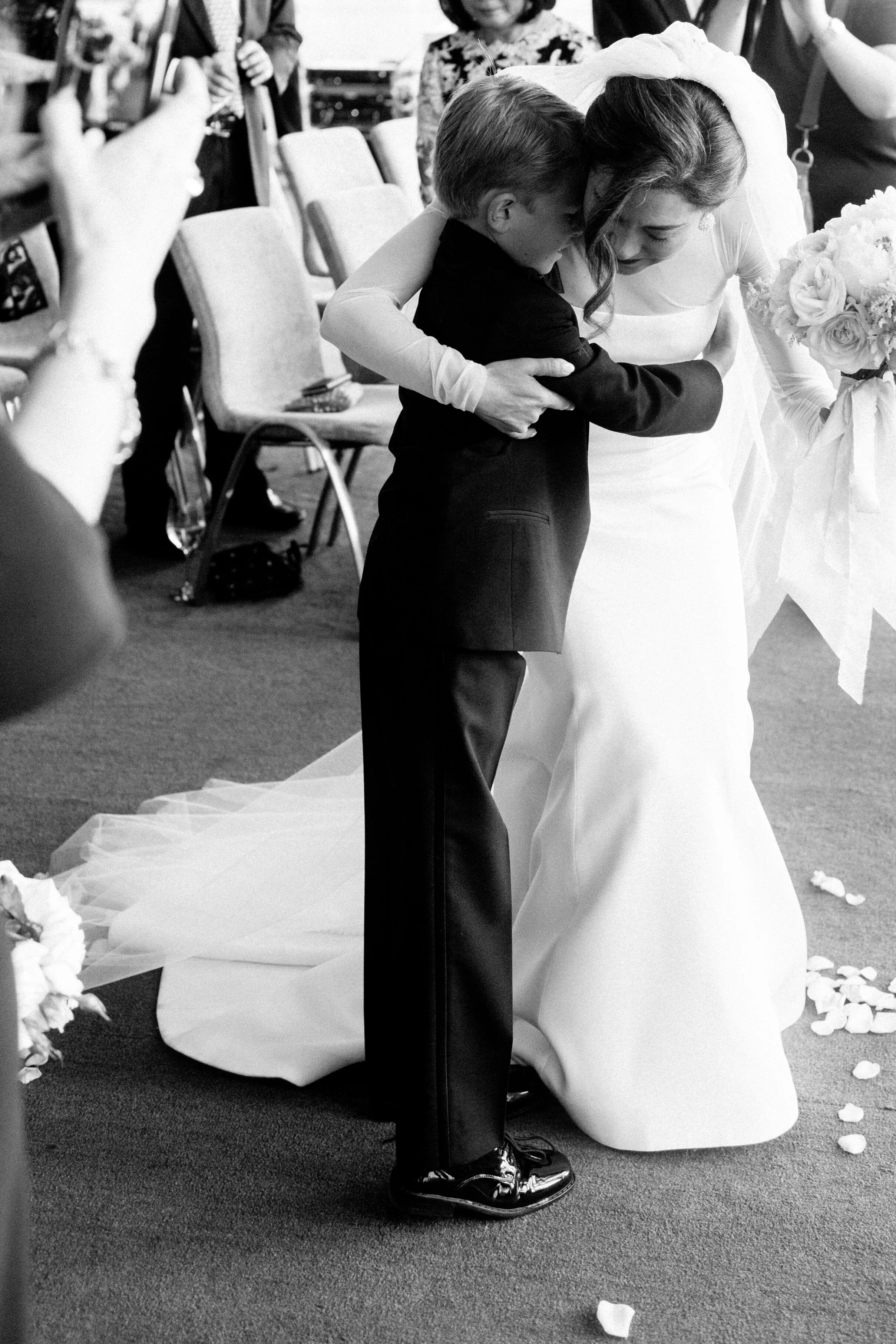 bride hugs little boy end of aisle 