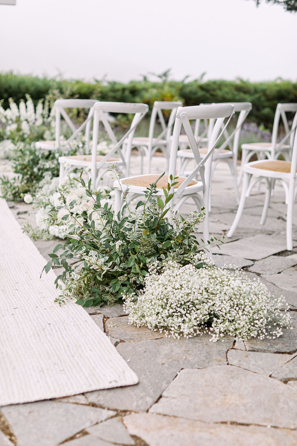 mixed white flowers on ceremony aisle ivory rug runner white crossback chairs