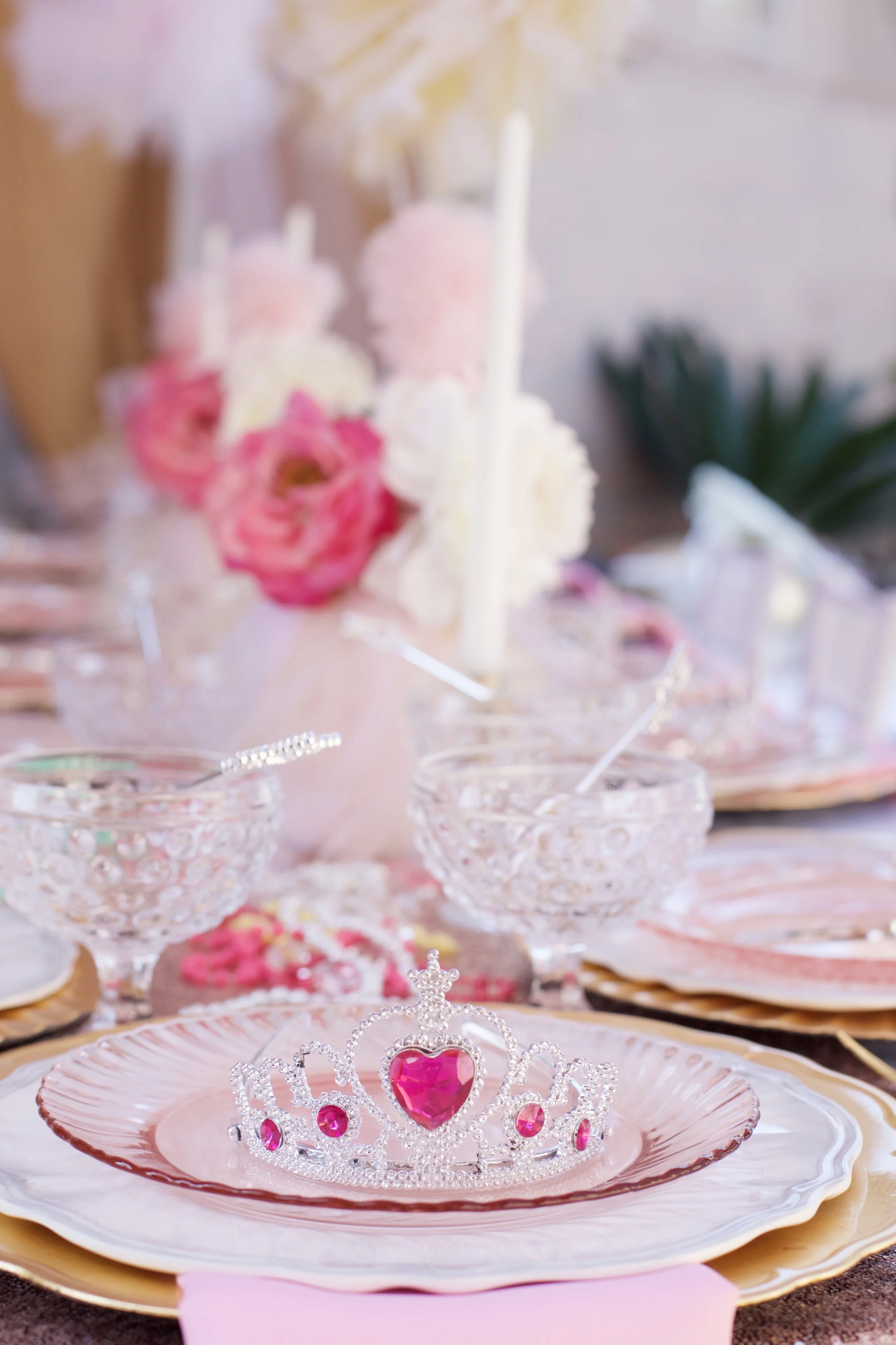 A rental collection with an elaborate ensemble of pink tutu centerpieces, white chiavari chairs, glittery runners, pink and white flowers, and sparkling tiaras that will dazzle even a Queen!