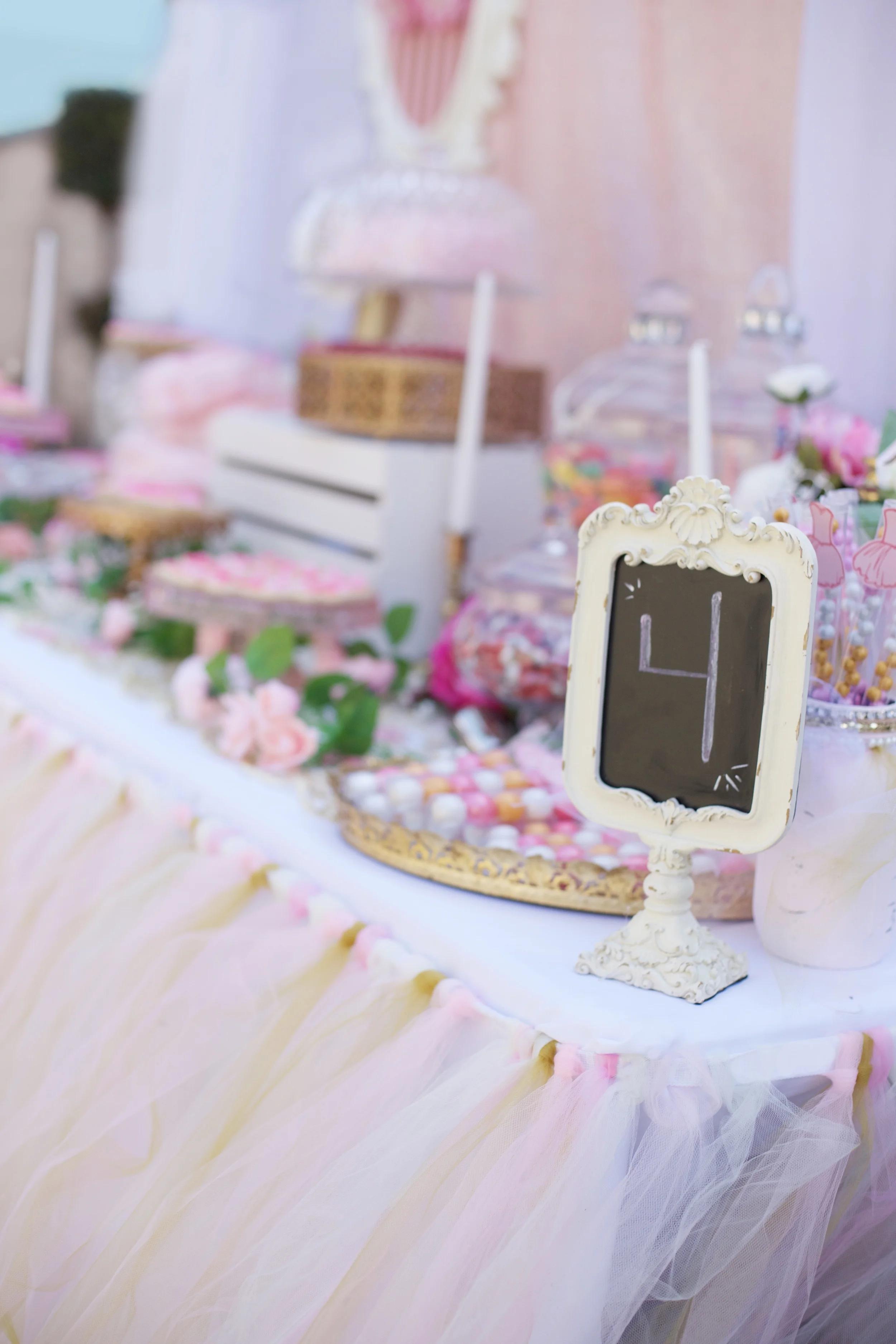 A rental collection with an elaborate ensemble of pink tutu centerpieces, white chiavari chairs, glittery runners, pink and white flowers, and sparkling tiaras that will dazzle even a Queen!