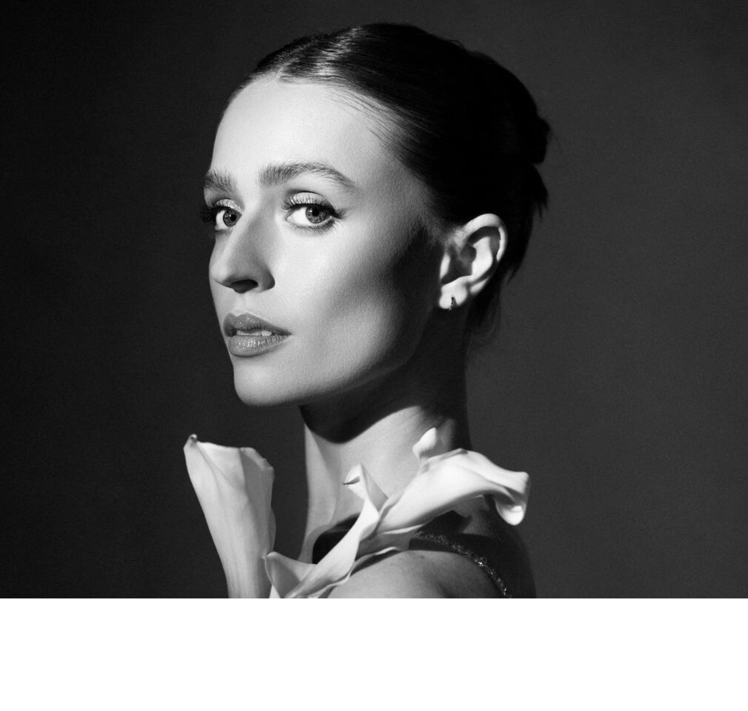 Black and white close-up profile of a woman with slicked-back hair, wearing a collared shirt and a jacket.