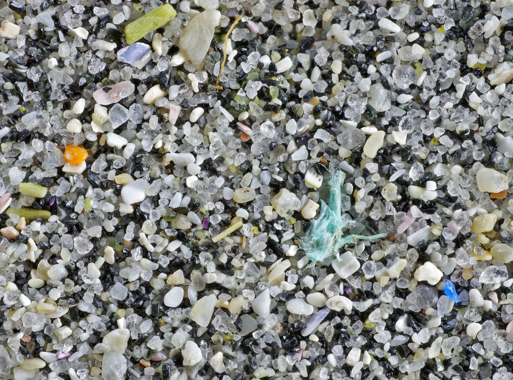 Et nærbilde av strandsand, avslører små biter av plast.