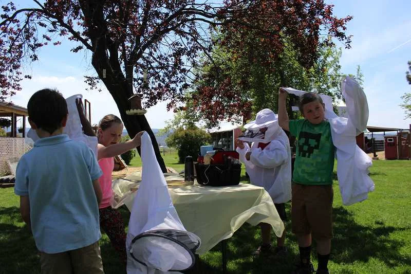 Students check out beekeeping equipment at one of the various stations set up on the Klann farm. Kids were invited to try on beekeeping suits.