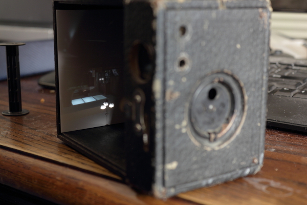 Kewpie No. 2 camera with the film holder removed. I've opened the shutter, here, and placed a piece of white paper at the back end (the focal plane). You can see - upside down - an image of my kitchen projected on the paper.