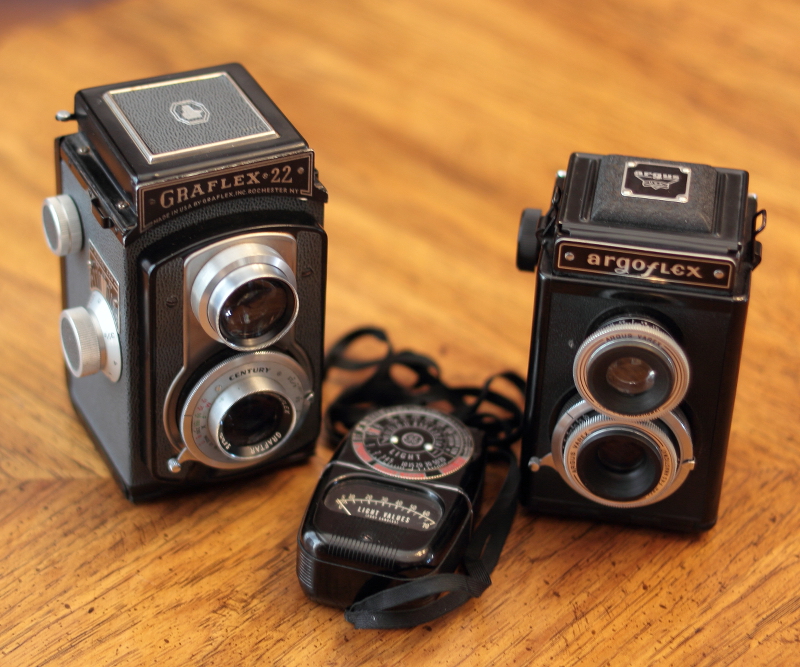 A Graflex 22 Model 200 Twin Lens Reflex camera (ca. 1955), an Argus Argoflex TLR, ca. 1945, and a GE light meter.