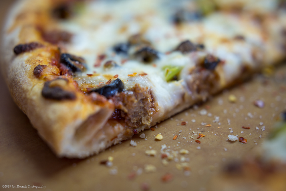 A delicious pizza on a wooden plank, with seasoning sprinkles.