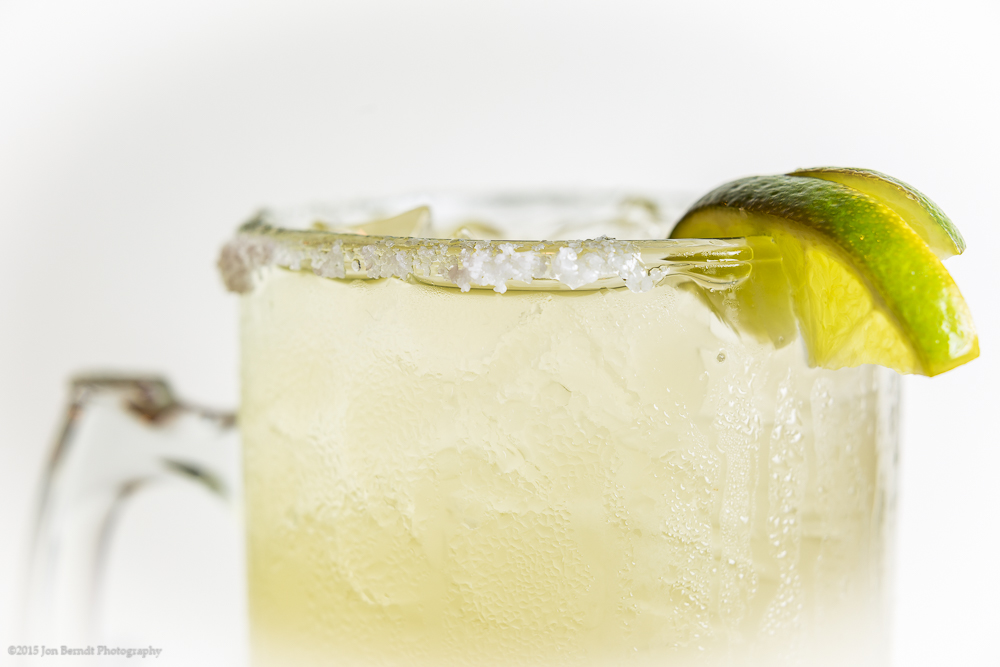 Margarita, with lime, backlit and shot against a white card.