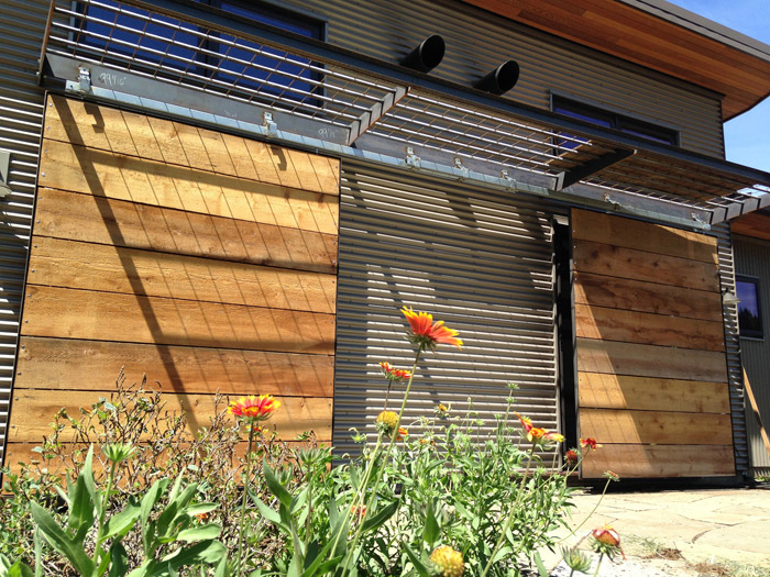 Sliding shutters mitigate the afternoon sun. Gaps in the reclaimed cedar let the breeze pass through. The shutters stack between the sliding glass doors when not in use.