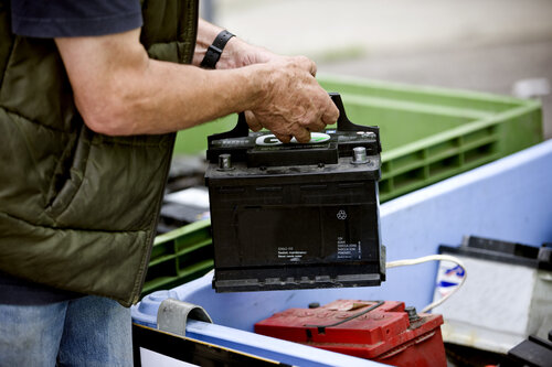 A senior man recycling a car battery