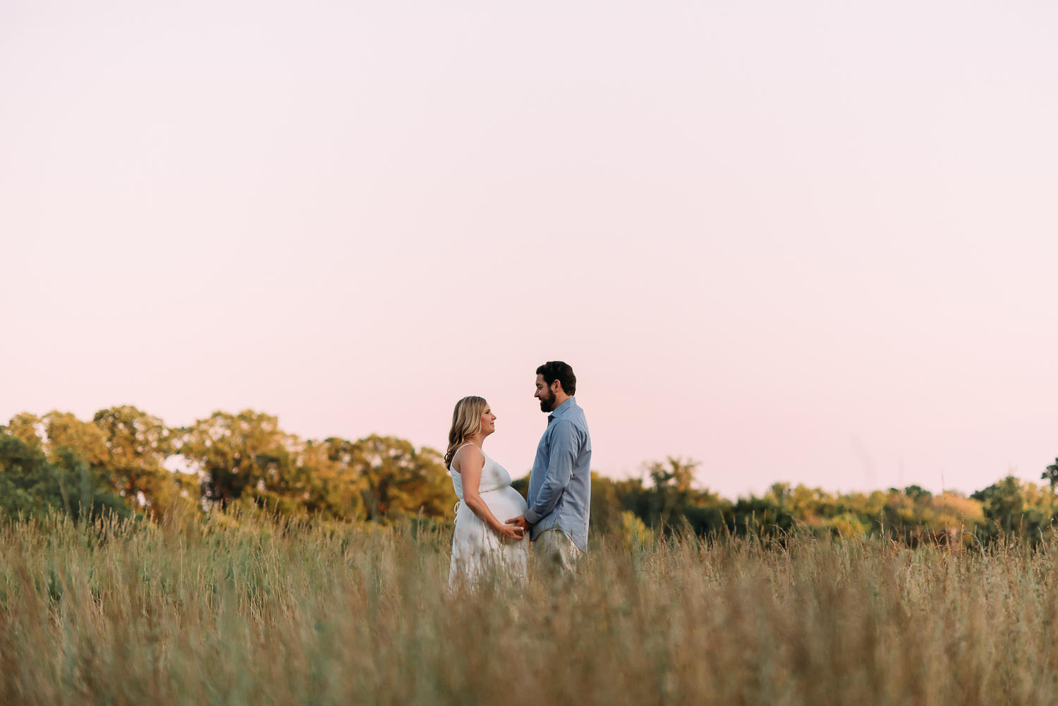 maternity photography pregnant woman in long white dress with husband in field at sunset Baltimore Photographer