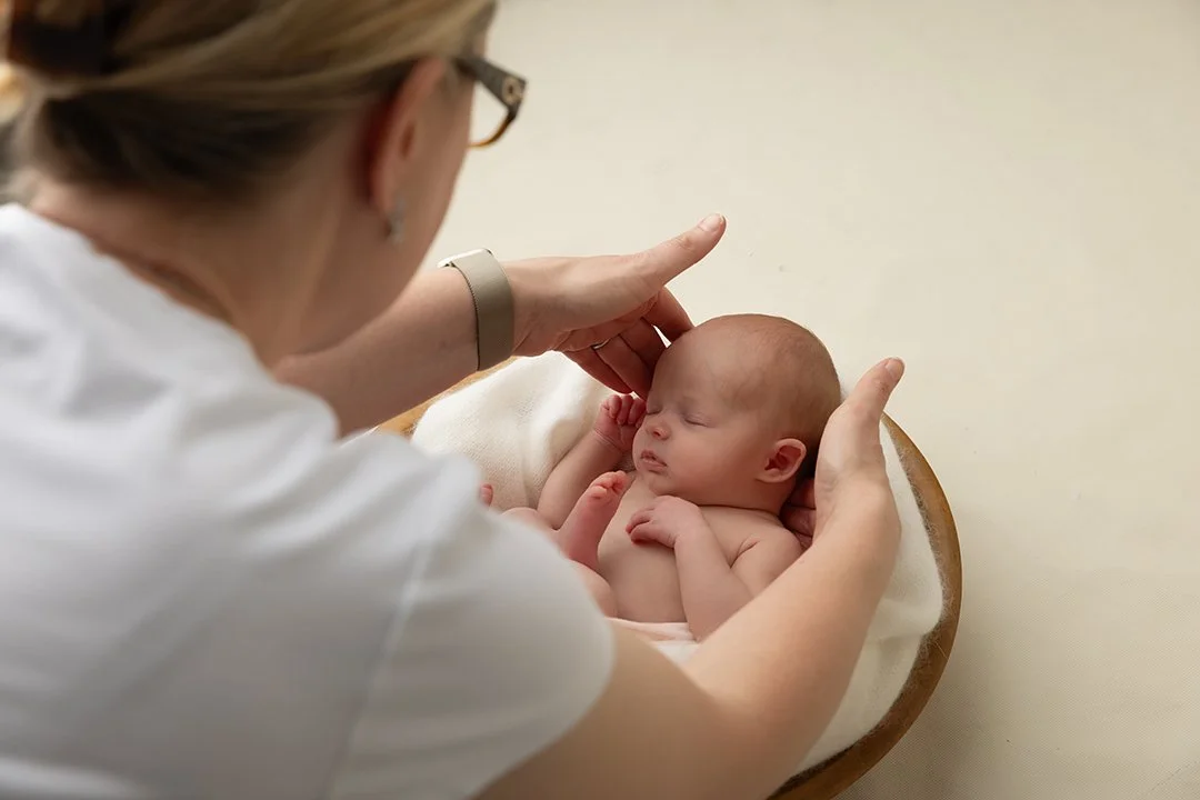 Ann Lyle posing a newborn baby