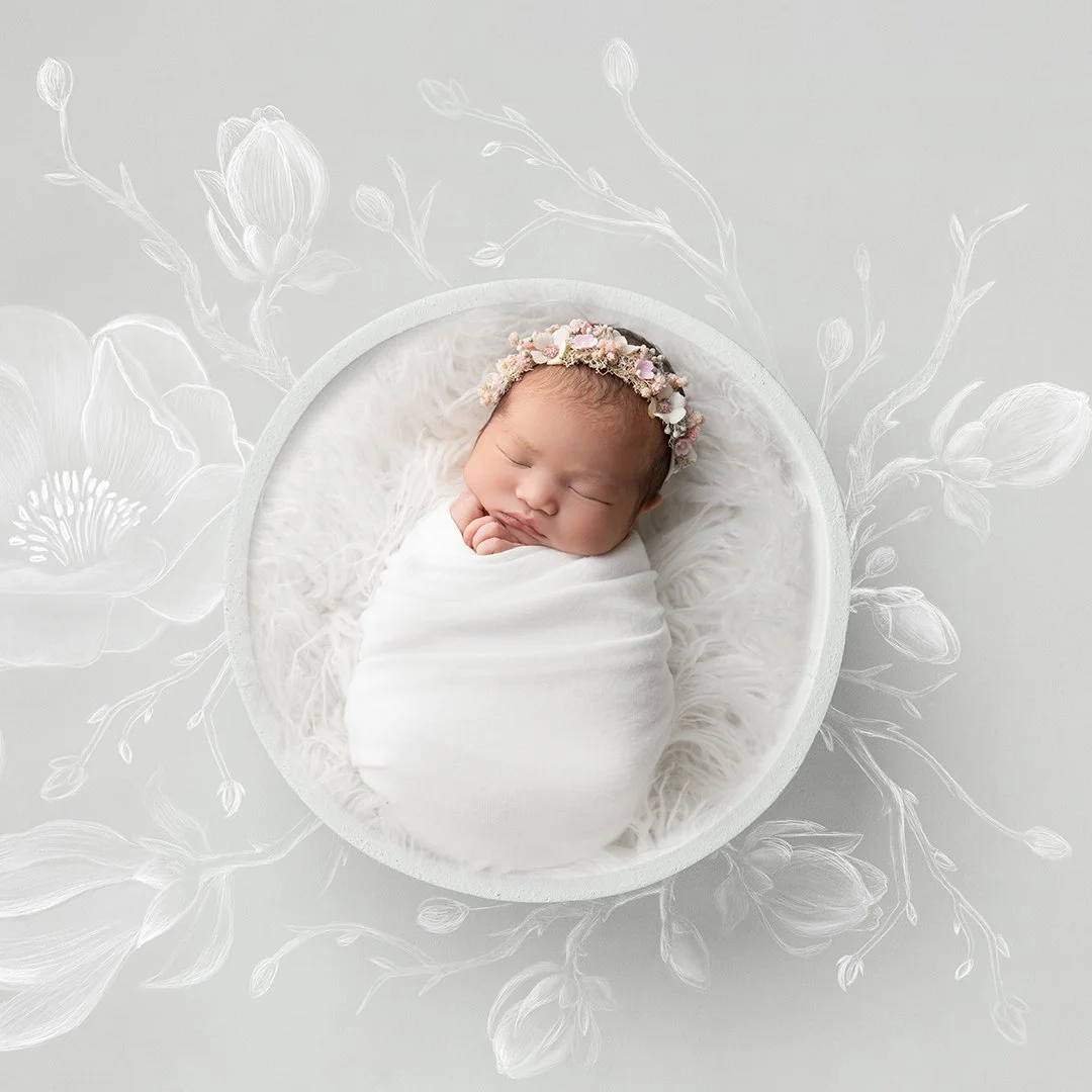 A sleeping newborn baby wrapped in a white blanket, lying in a round white basket with fluffy padding, wearing a floral headband, on a white textured background with floral line art.