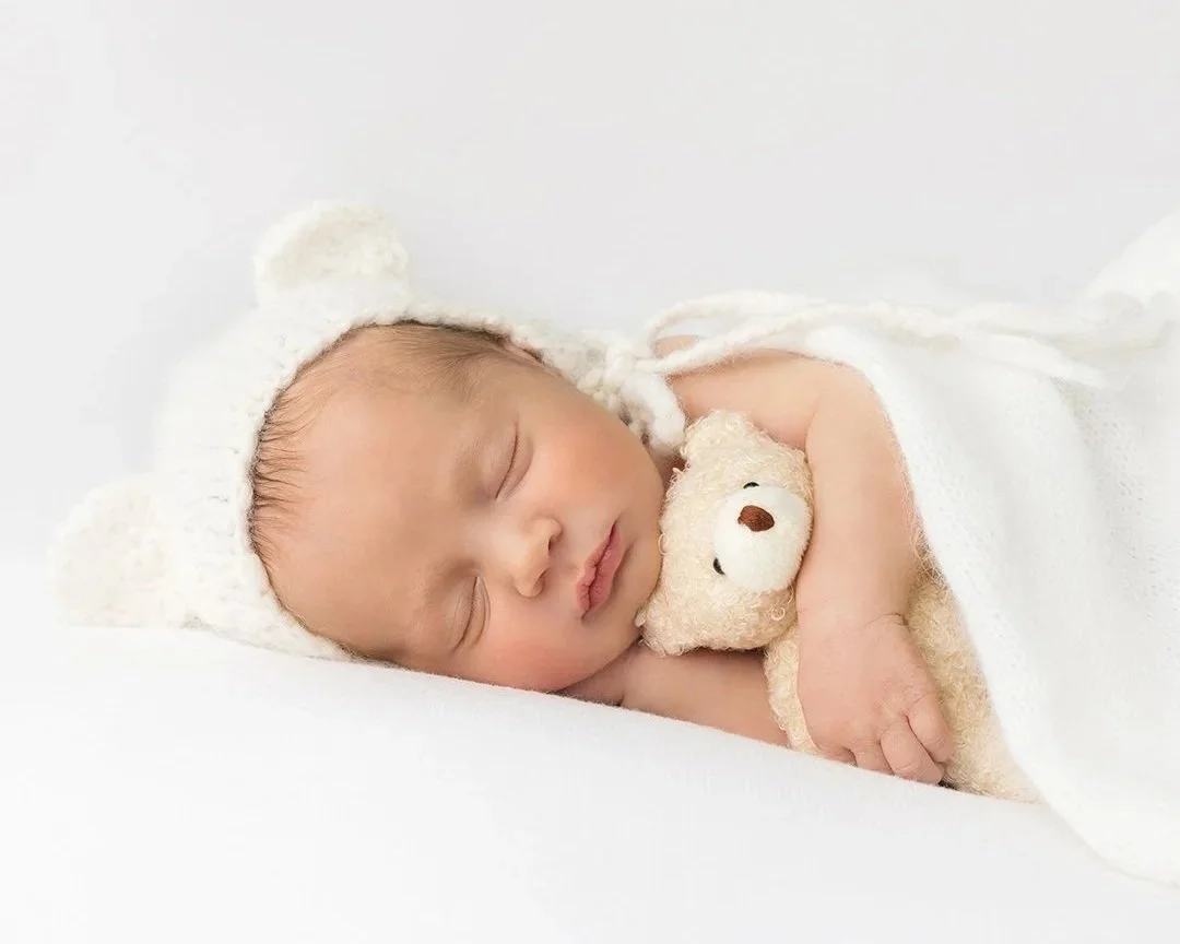 a newborn baby snuggling a teddy bear